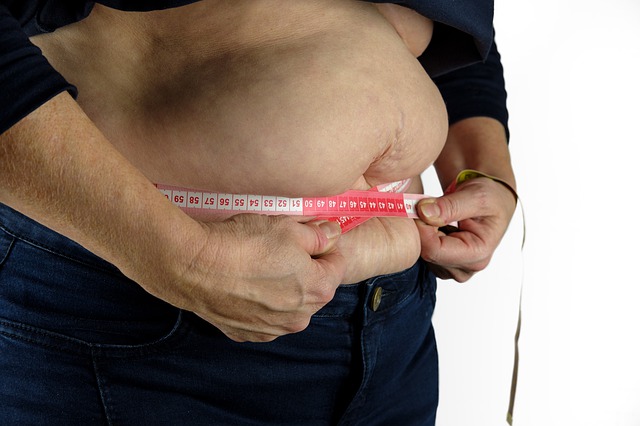 obézní muž si měří obvod pasu